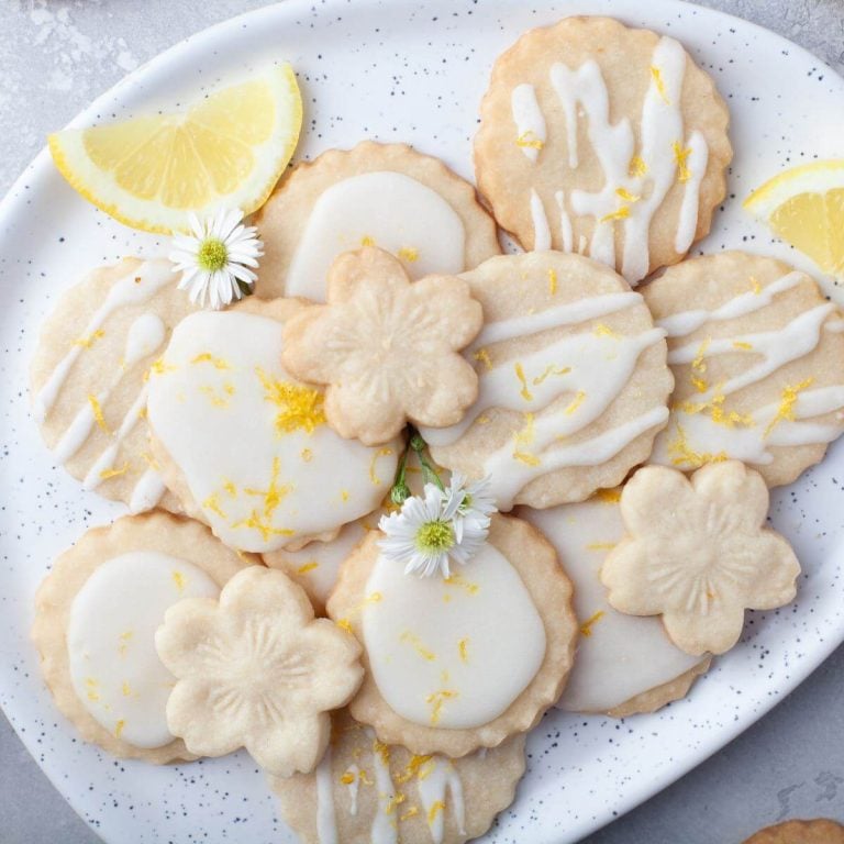 A platter of decorated cookies is garnished with flowers and lemons.