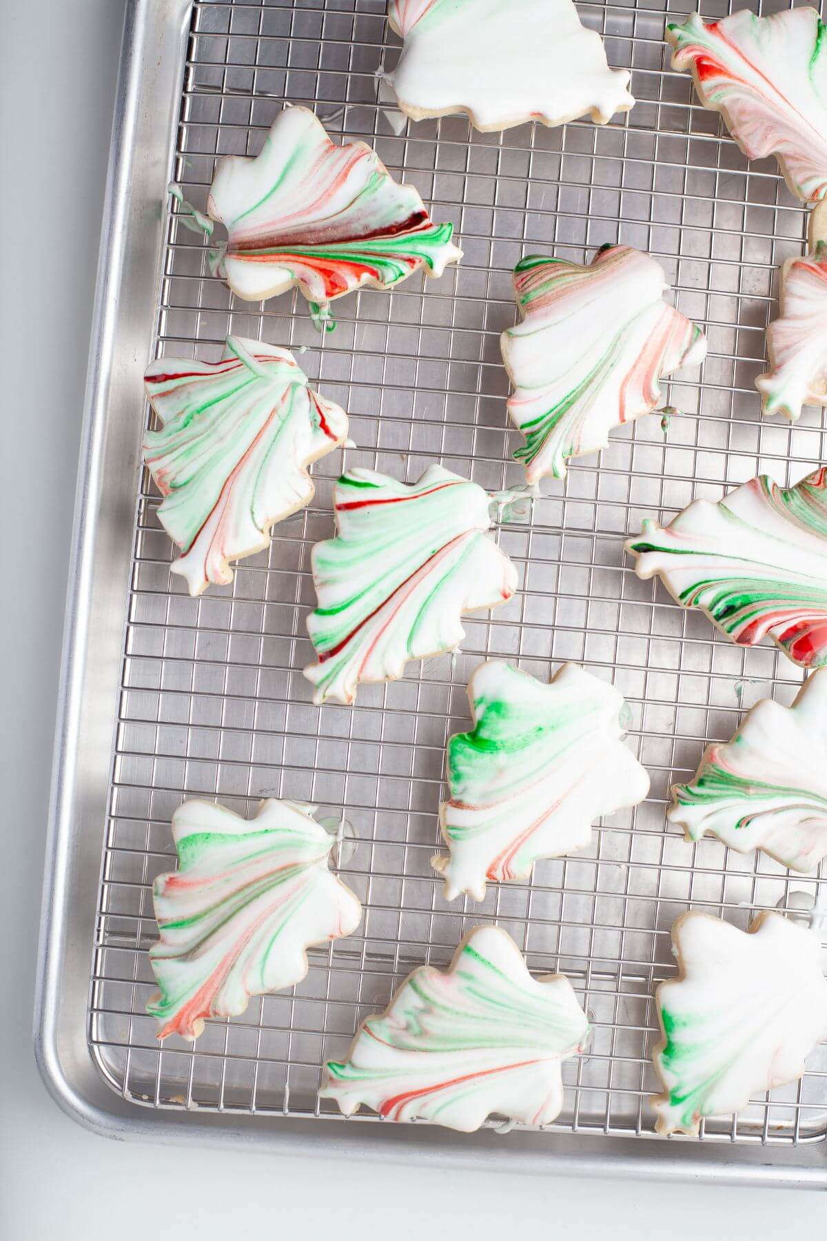 Christmas tree cookies lay on wire rack.