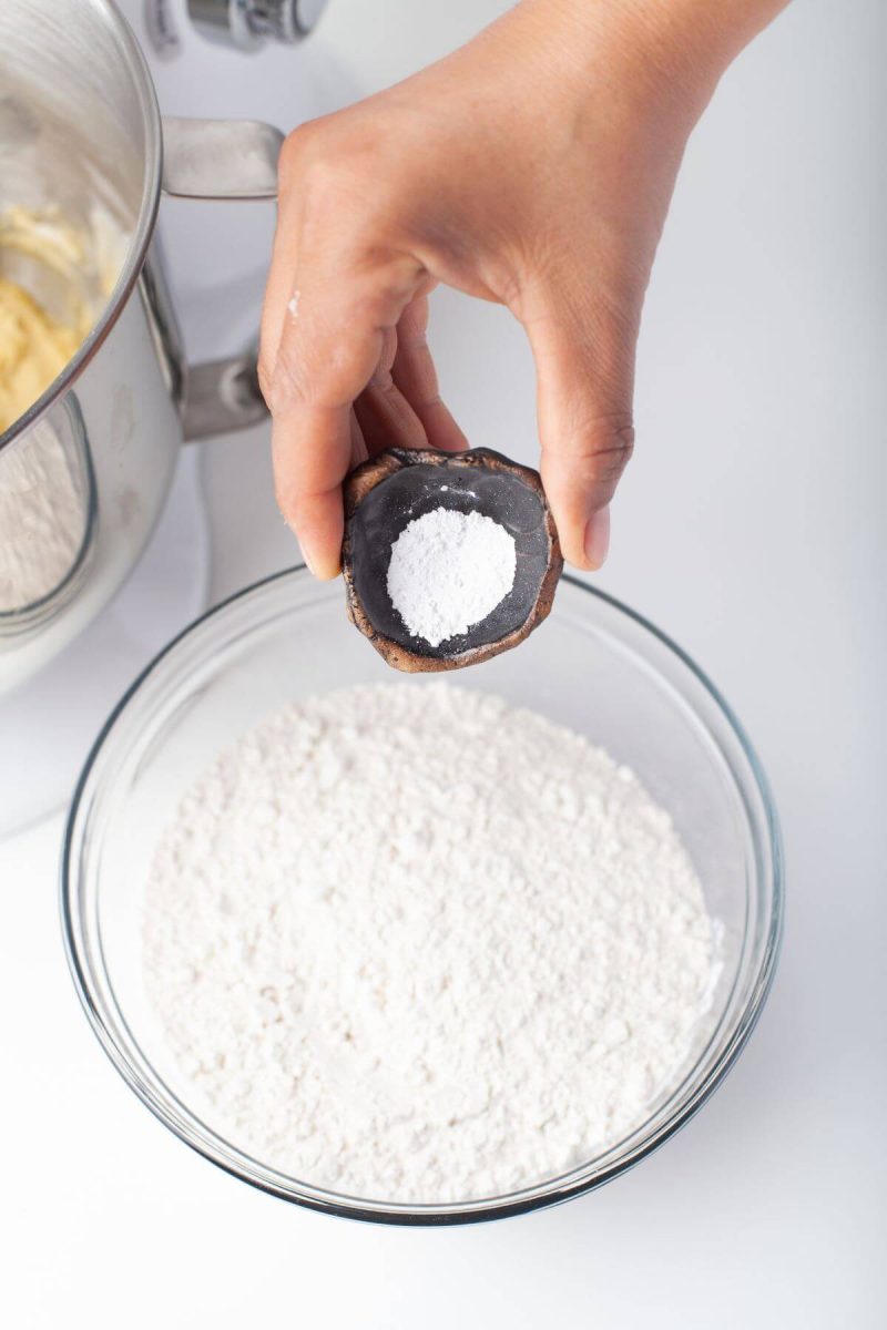 A hand is pouring salt into ingredient bowl.