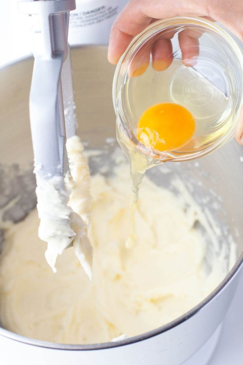 A hand is pouring an egg into the mixture.