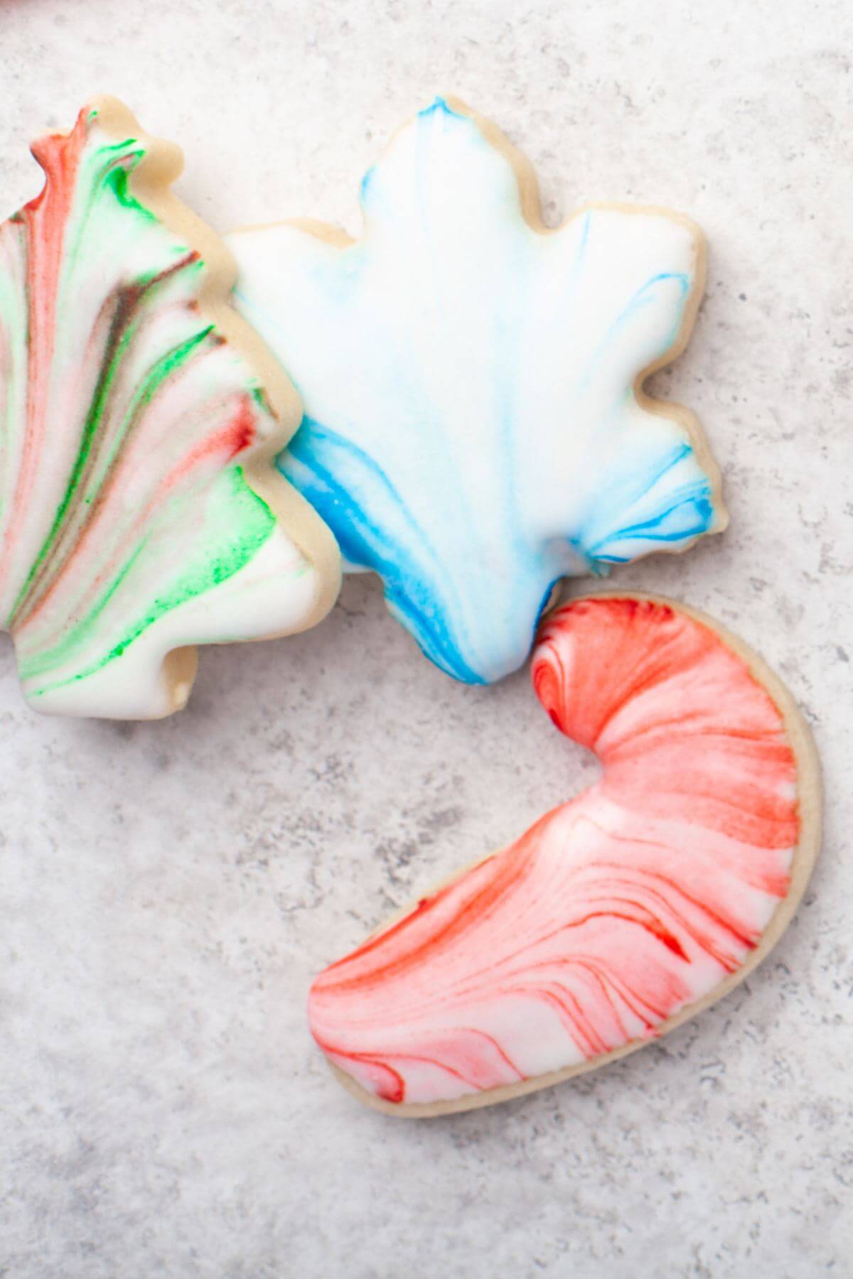 Close up of three shapes of cookies: candy cane, Christmas tree, and leaf.