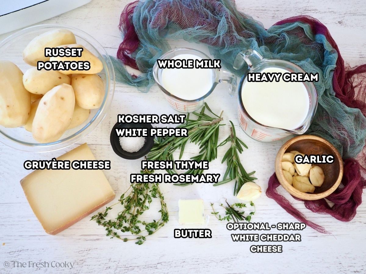 Labeled ingredients for Potatoes au gratin, L-R peeled Russet potatoes, whole milk, heavy cream, garlic cloves, rosemary, thyme, butter, gruyere cheese, salt.