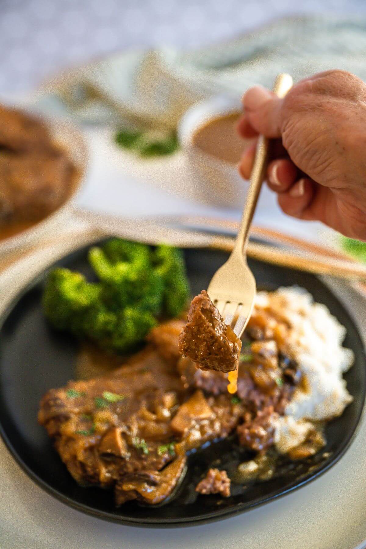 Someone has grabbed a piece of Cube Steak and Gravy on their fork over their plate.