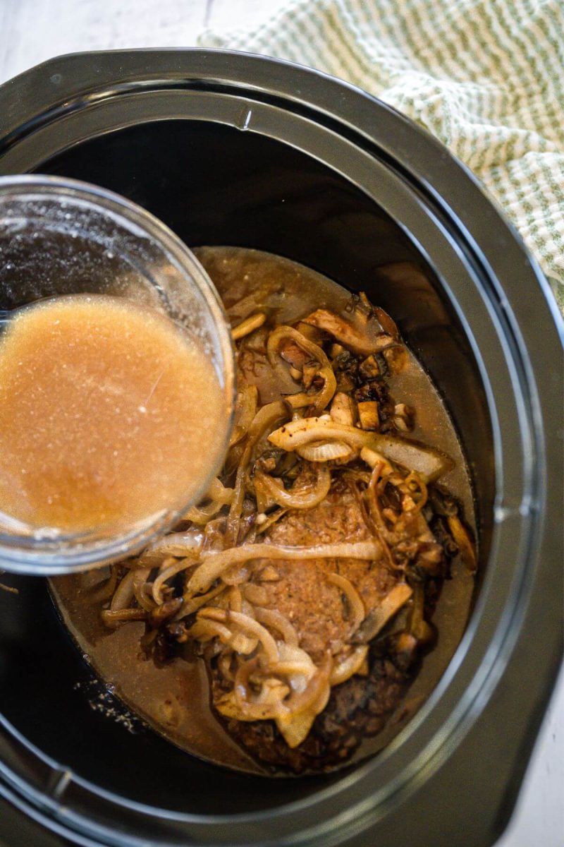 A small mixing bowl pours steak juice into crockpot.