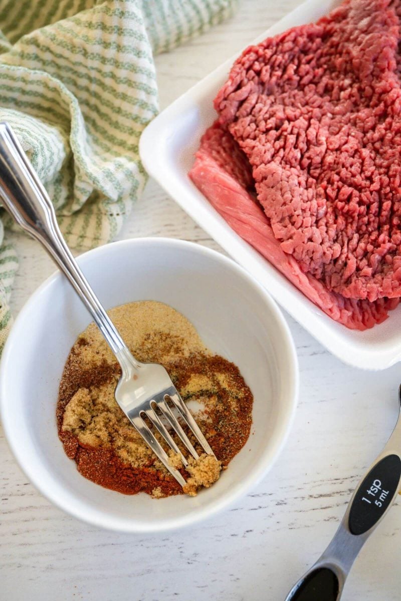 Dry seasonings are in bowl next to raw cube steaks.