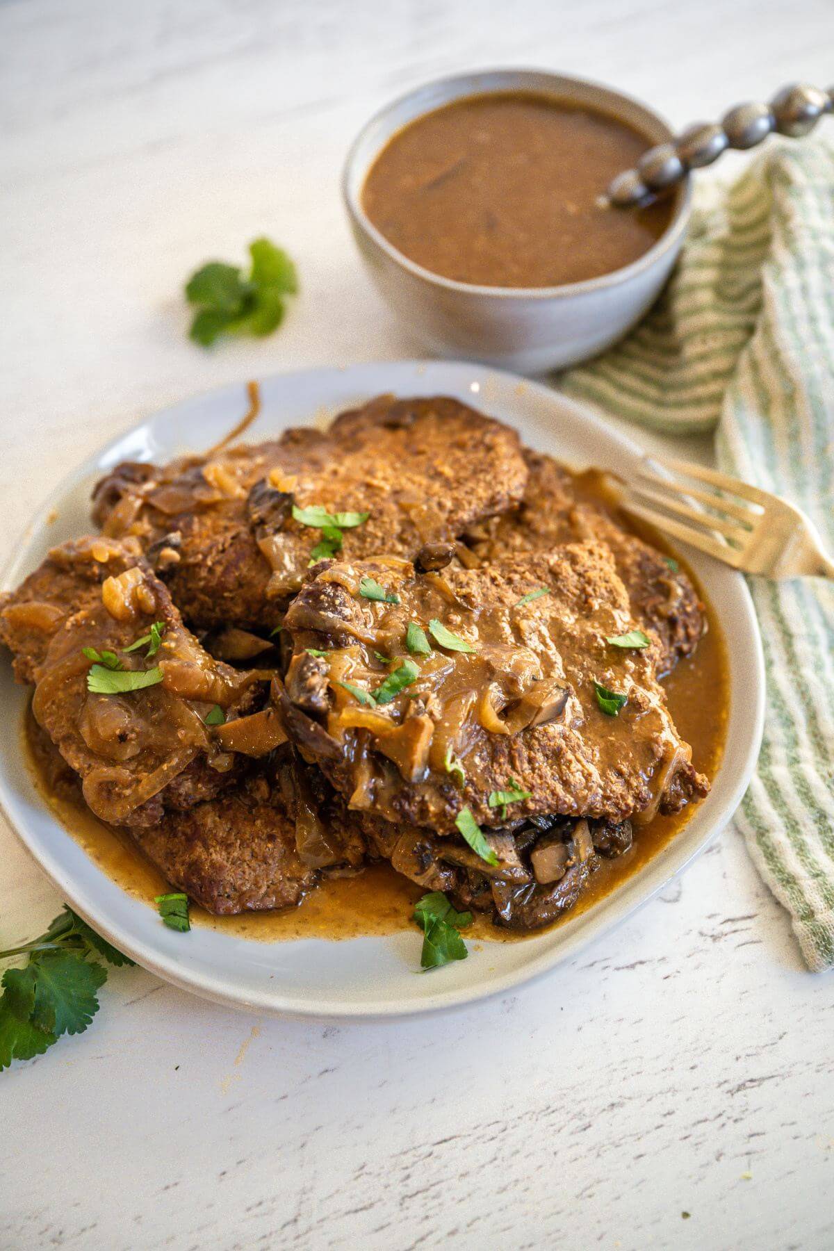 Cube Steak and Gravy fills a plate with gravy bowl behind it.