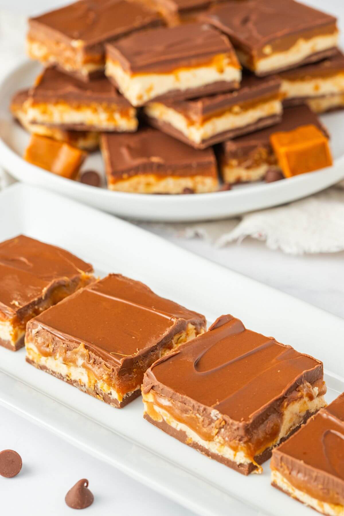 A diagonal row of fudge bars are in front of full plate of fudge.