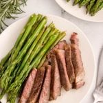 Slices of ribeye steak on plate with asparagus.