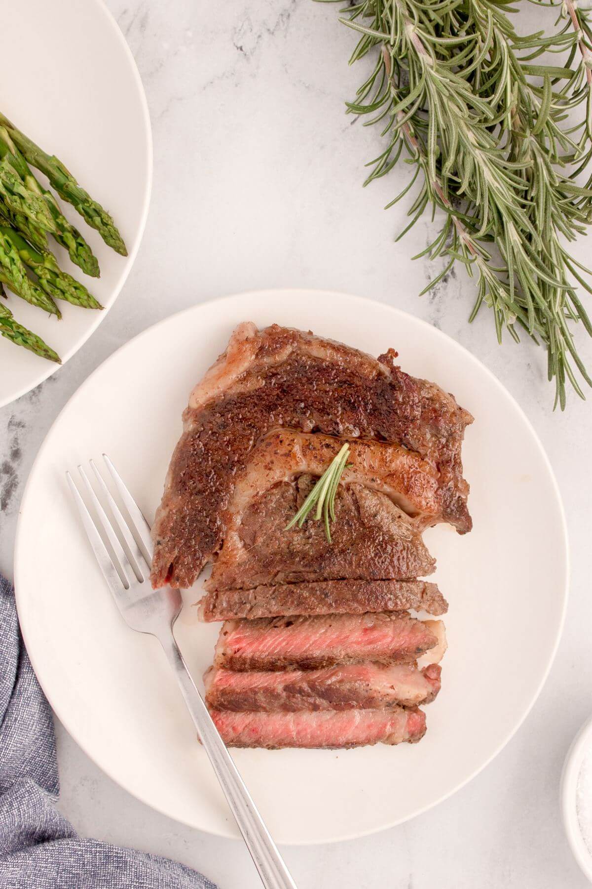 Sous Vide Ribeye Steak by fork on plate by side dishes.