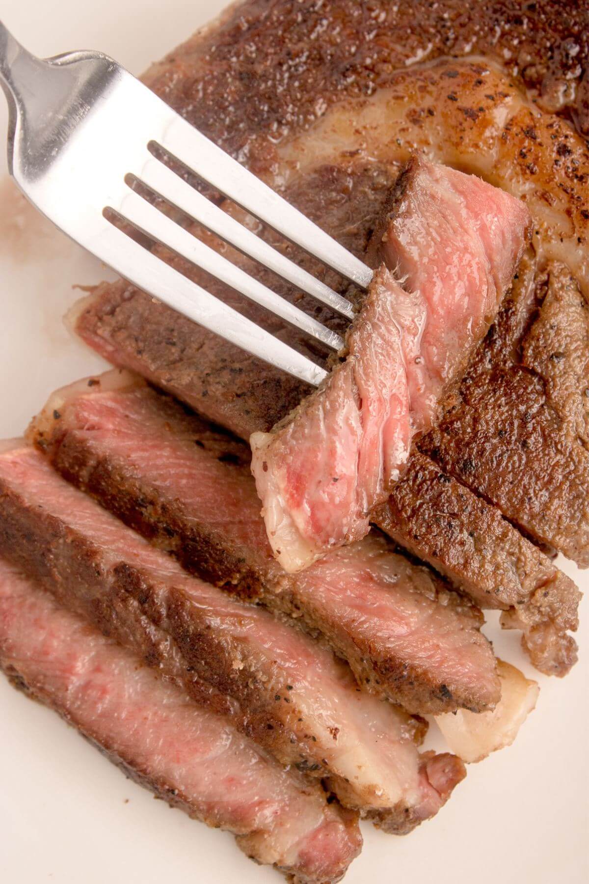 Ribeye slices pieces on plate with fork.