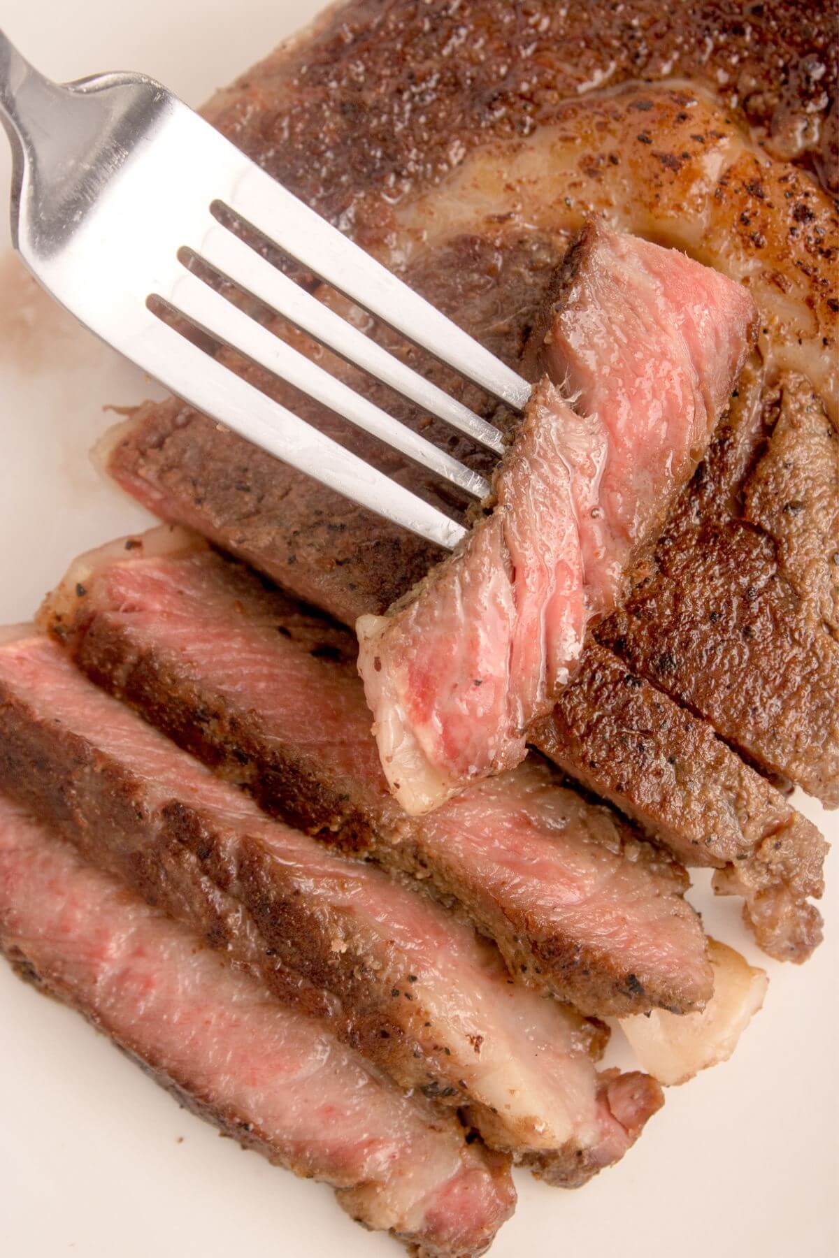 Ribeye slices pieces on plate with fork.