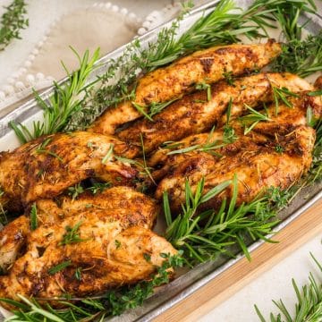 Multiple, air fryer turkey tenderloins juicy and on platter garnished with fresh rosemary.
