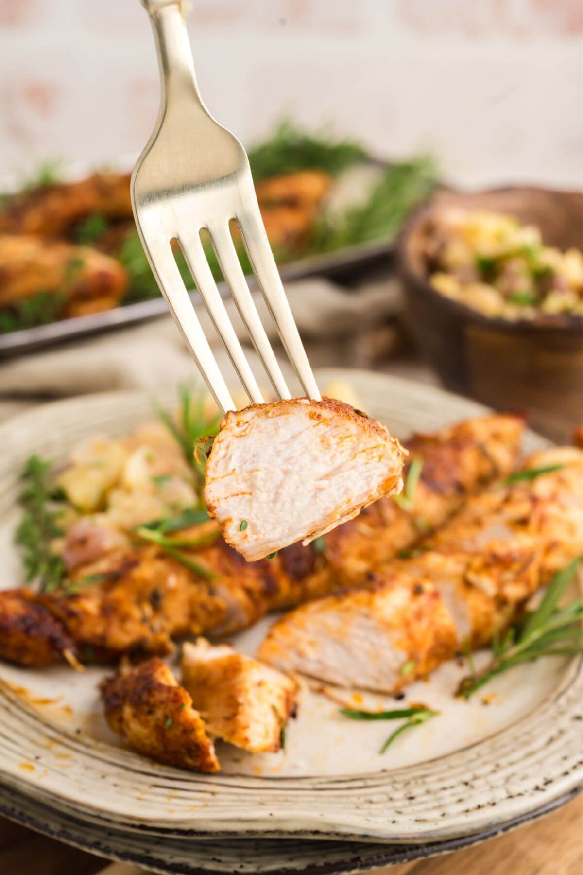 Turkey tenderloins on plate while someone raises a piece up with a fork.