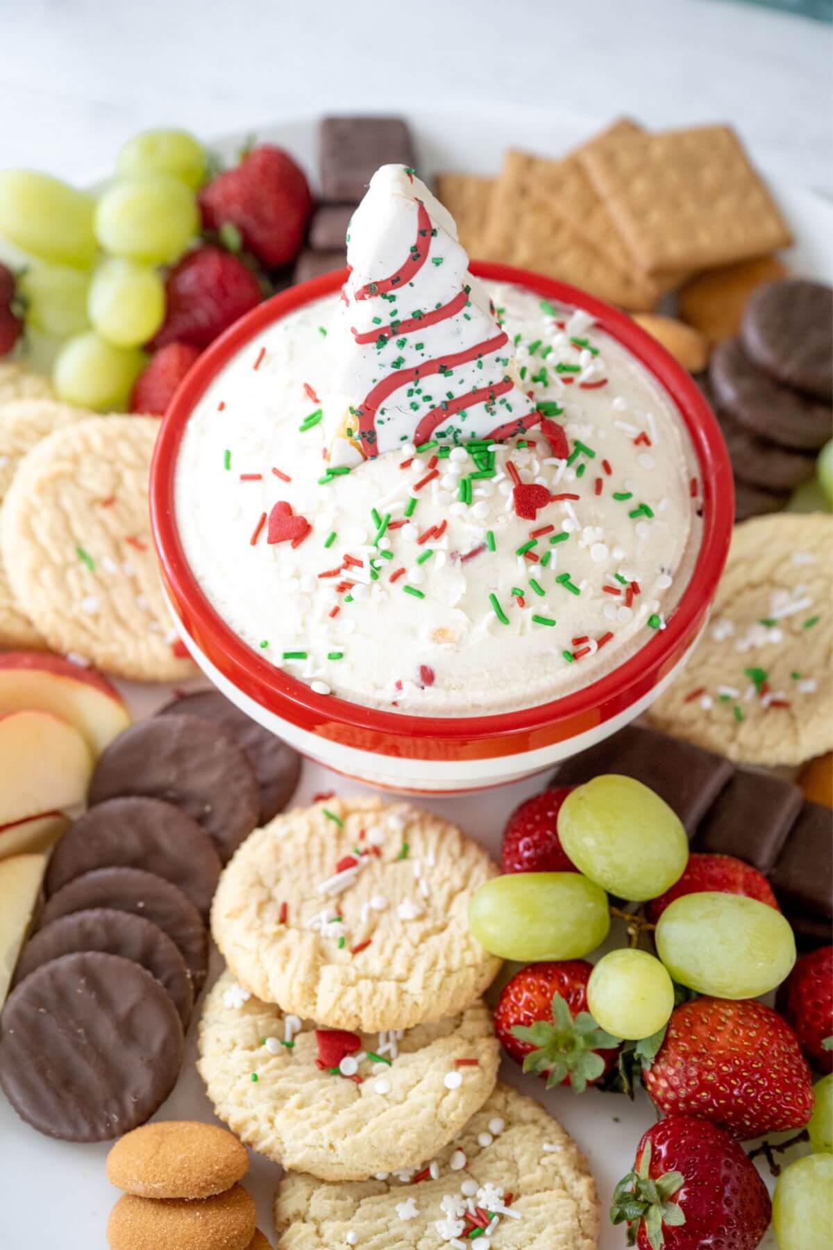 Bowl of dip in middle of platter with cookies, fruit, chocolate dippers.