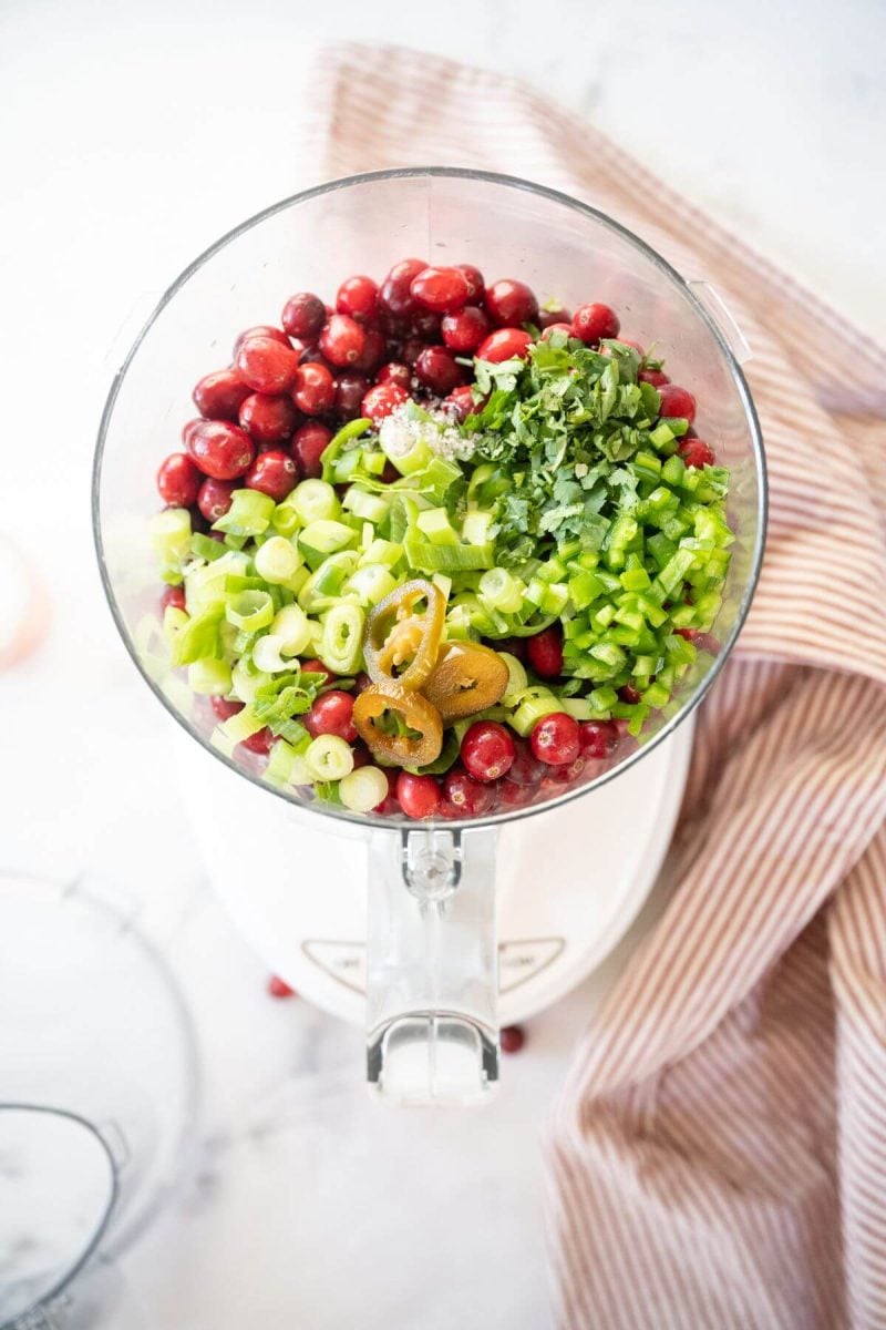 Cranberries, green onions, sweet hot jalapenos and regular jalapenos in bowl of food processor.