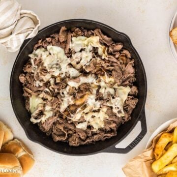 Melted cheese on top of shaved steak.