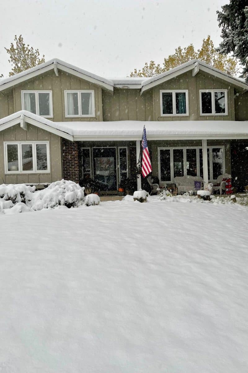The front of a home with an American flag, all covered in snow. 