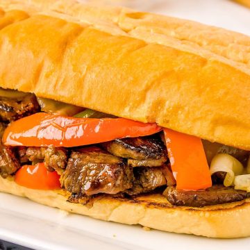 A close up view shows peppers, onions, and beef inside the sandwich.