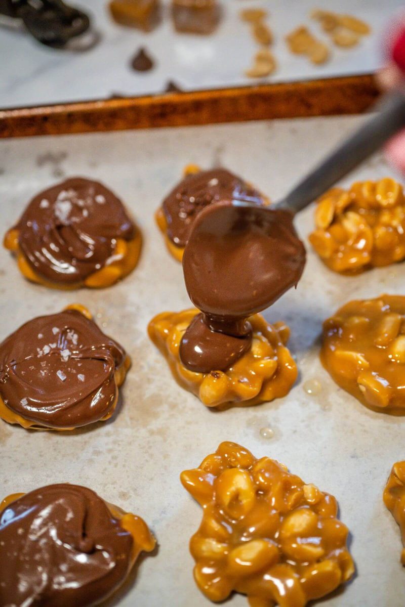 A spoon drips chocolate on a peanut cluster.