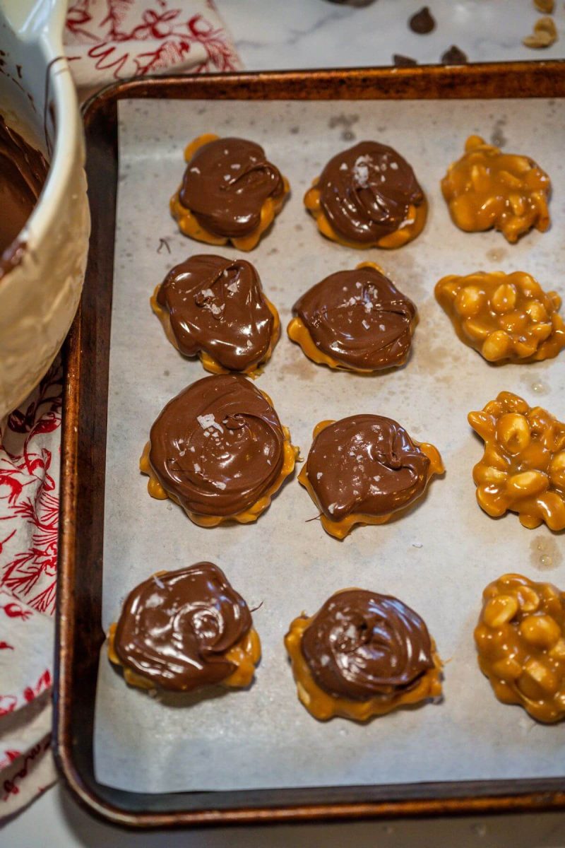 A baking pan has peanut clusters, half of which have chocolate on top.