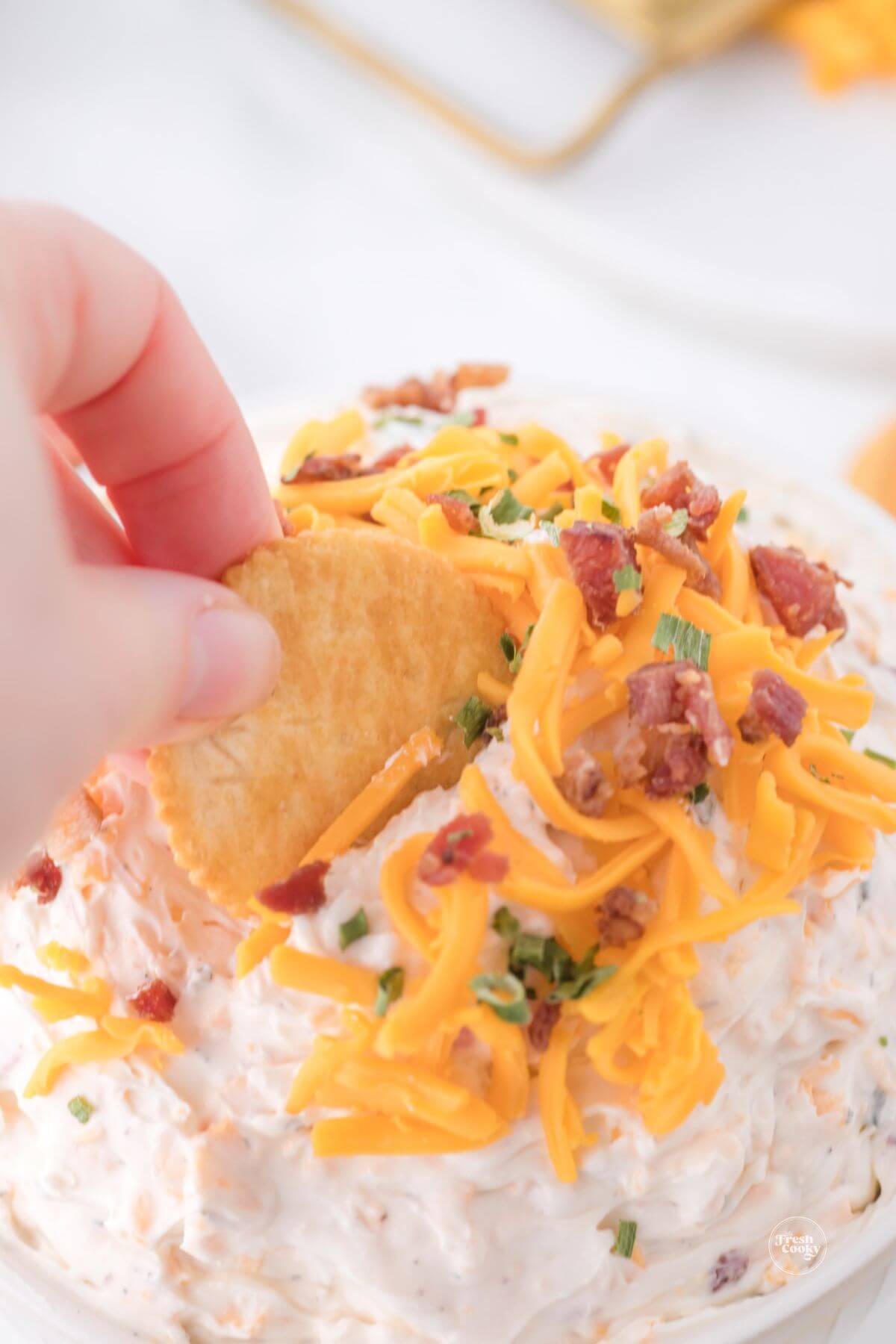 Hand dipping Ritz cracker into cowboy cream cheese dip.
