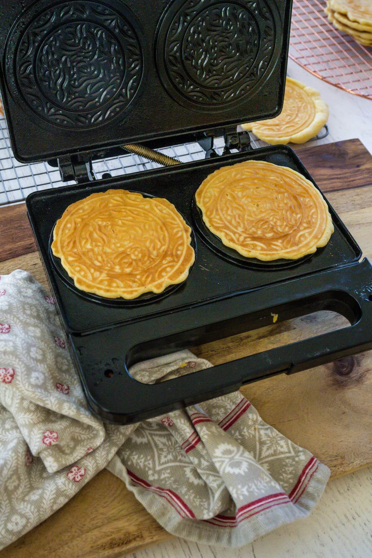 Cooked Pizzelle cookies lay on iron.