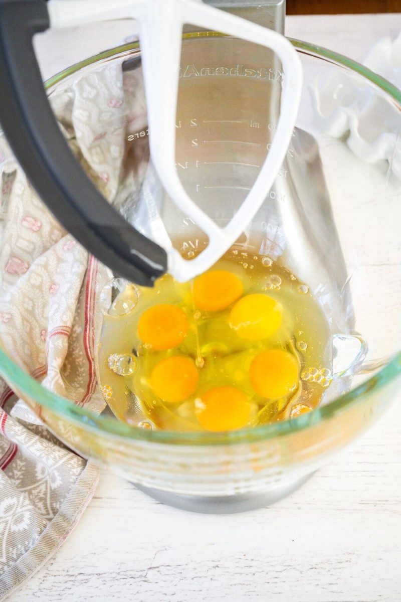 Raw eggs rest in bowl of stand mixer.