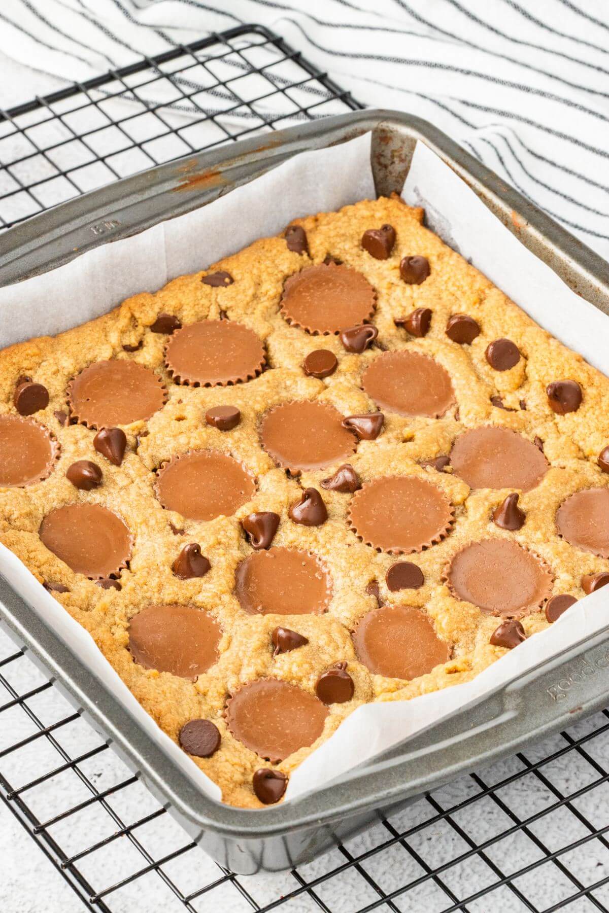 A pan of baked blondies rests on wire rack on table.
