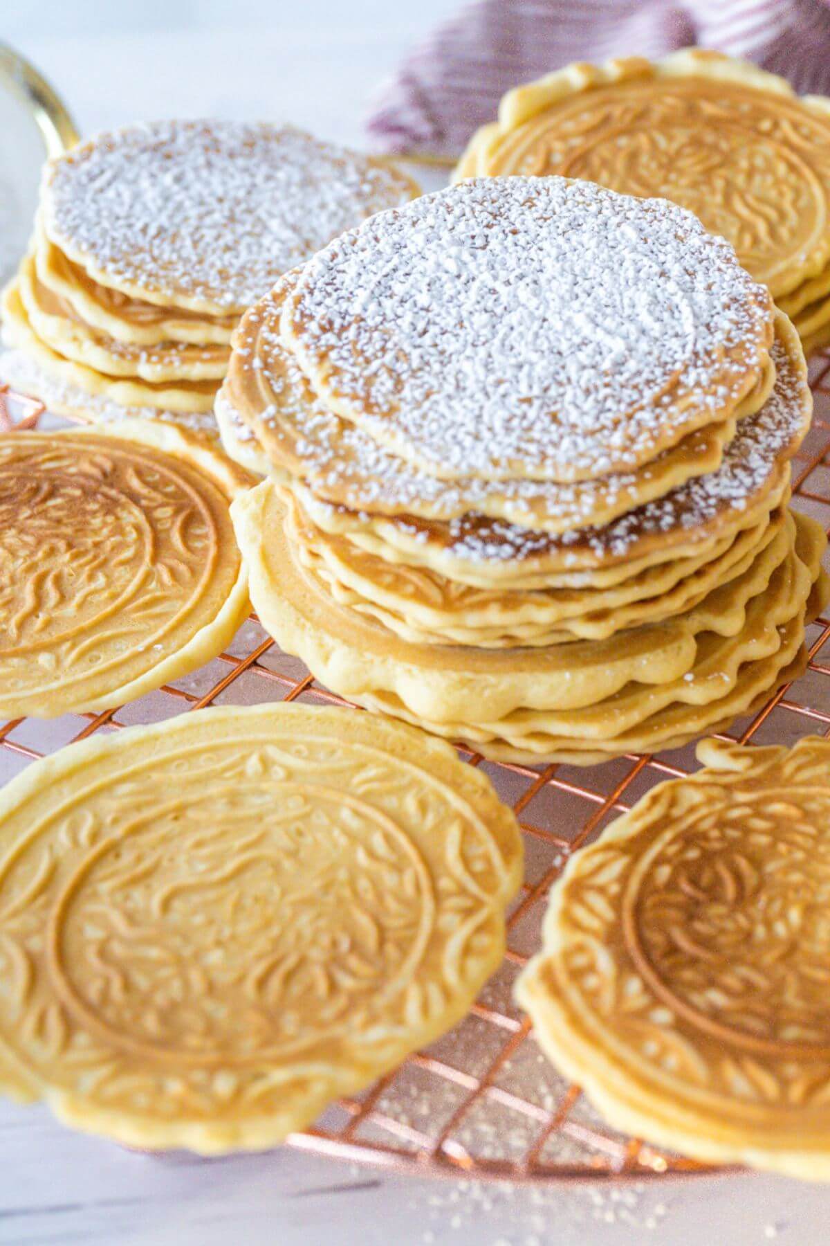 A close up view shows detail on Pizzelle cookies and powdered sugar on top.