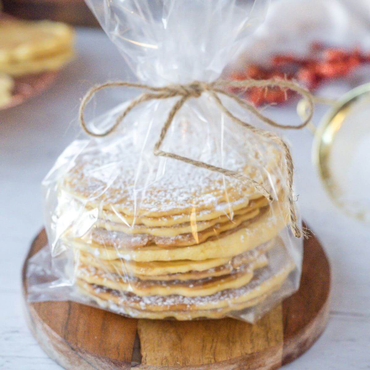 A clear giftwrapped tower of Pizzelles rests on wooden display dish.