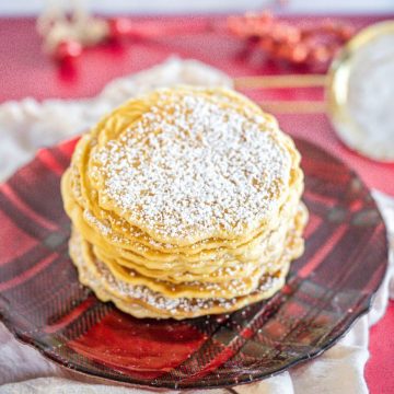 A powdered stack of cookies sits on a festive red plaid plate.