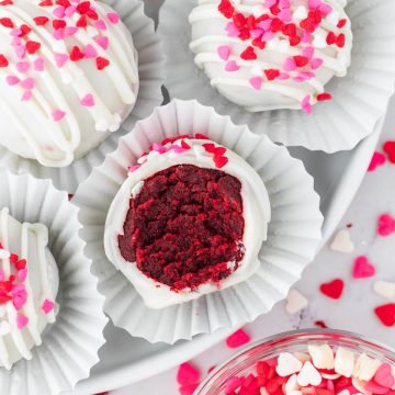 Cupcake liners hold sprinkled cake pops with one showing the inside.