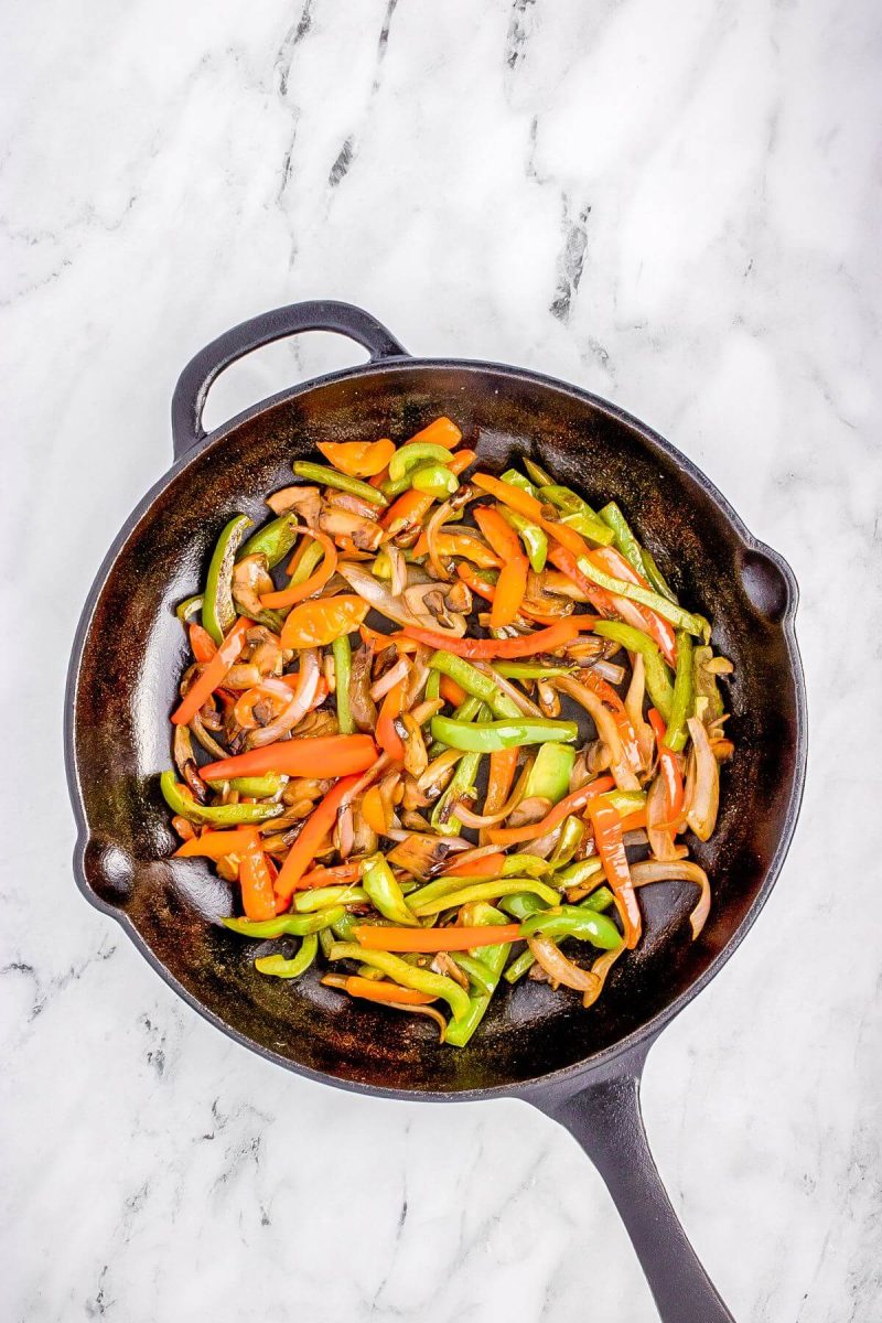 Bell peppers and mushrooms cook in skillet.