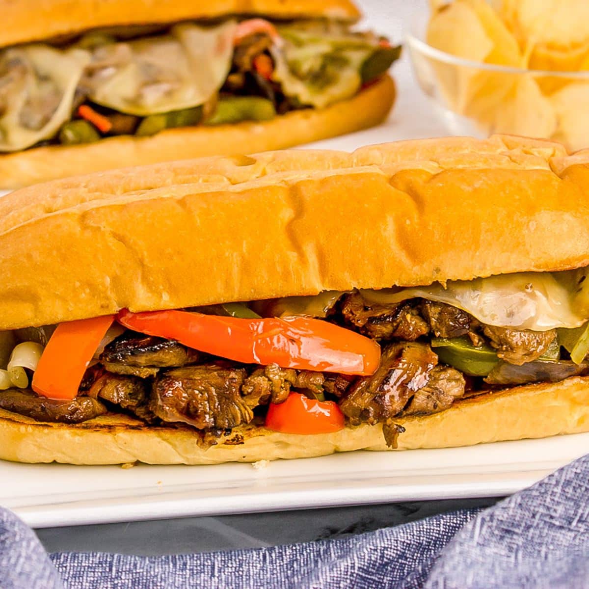 Beef Tenderloin Sandwiches on plates with potato chips behind.