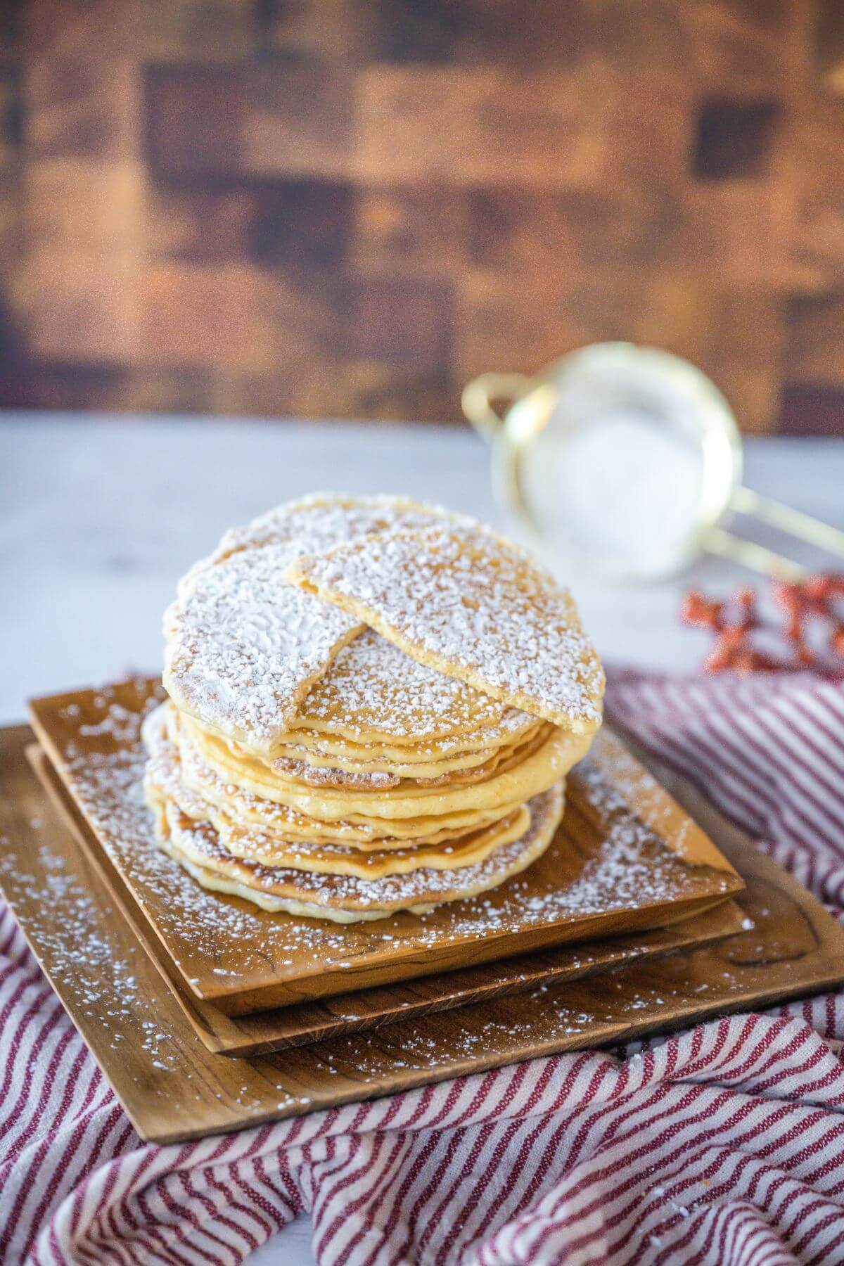 Cookies are stacked on top of each other and dusted with powdered sugar.