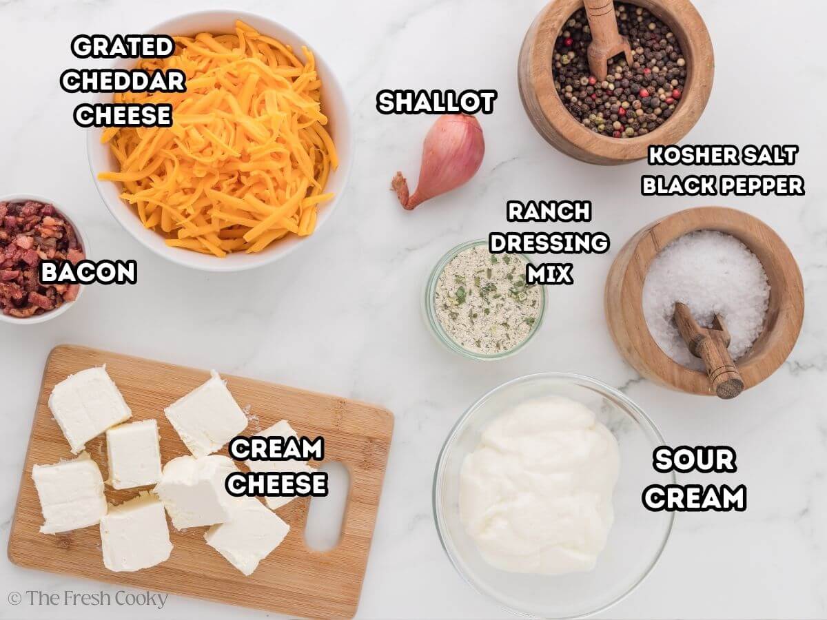 Cowboy crack dip labeled ingredients L-R bacon bits, shredded cheddar, shallots, ranch dressing, sour cream and cream cheese.