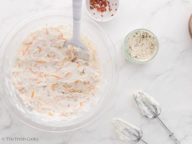 Mixing in cheeses and ranch dressing mix to cream cheese dip.