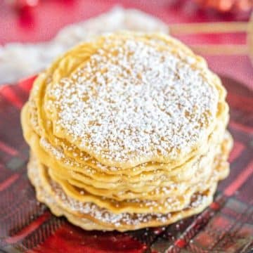 A powdered stack of cookies sits on a festive red plaid plate.