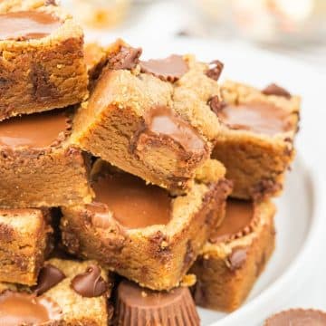 Stacked peanut butter cup blondies on a plate.