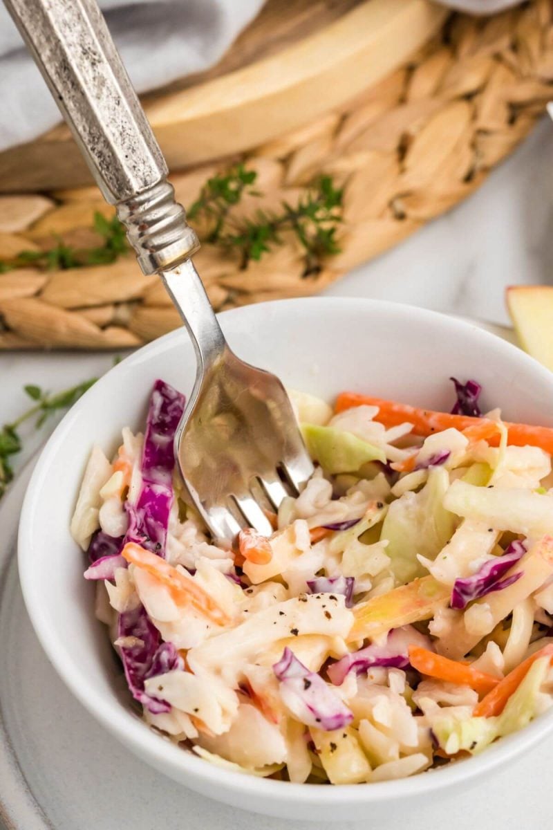 Apple Coleslaw served in bowl with fork.