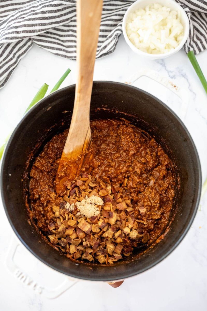 Some brown sugar is mixed into ground beef in pot.