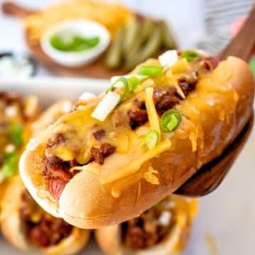 A spatula holding up a baked chili cheese dog.