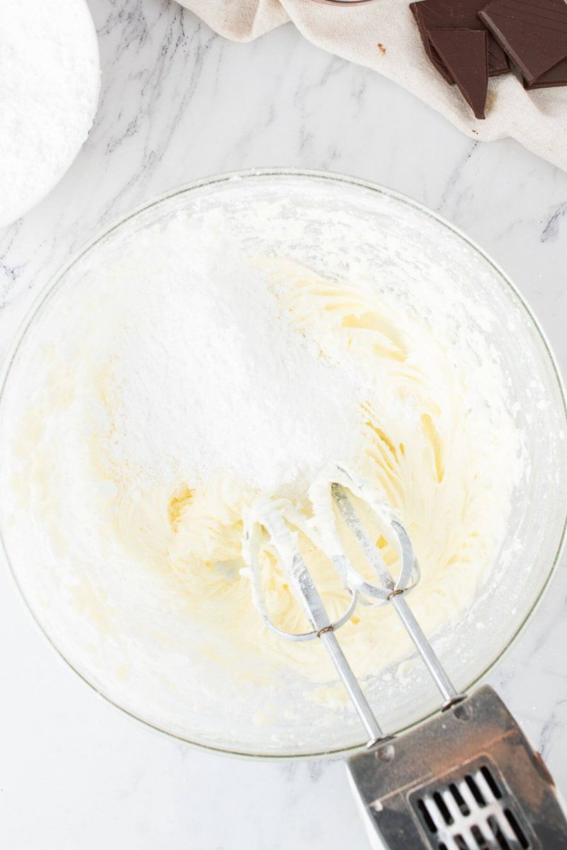 Powdered sugar sits on butter icing as it is mixed into the icing.