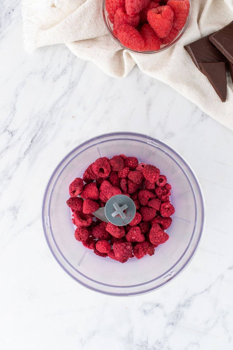 Whole, freeze-dried raspberries are in food processor.