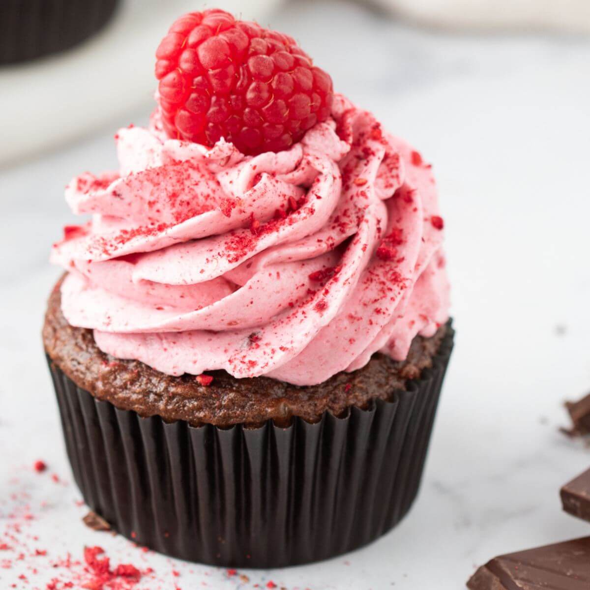 A single chocolate cupcake has double height in pink frosting on top.