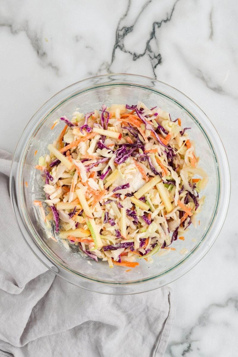 A glass mixing bowl holds coleslaw mix.