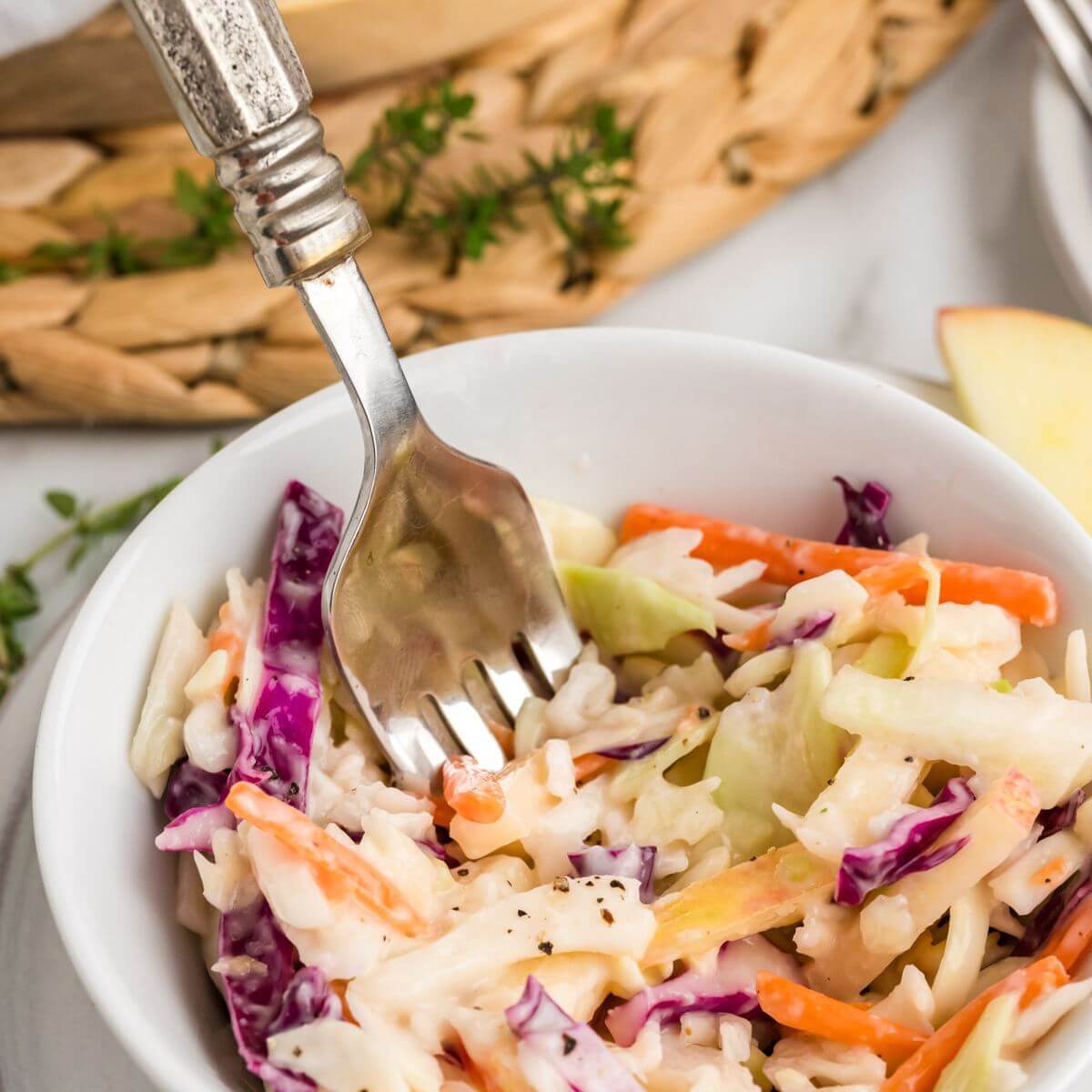 A fork dives into a bowl of Apple Coleslaw.