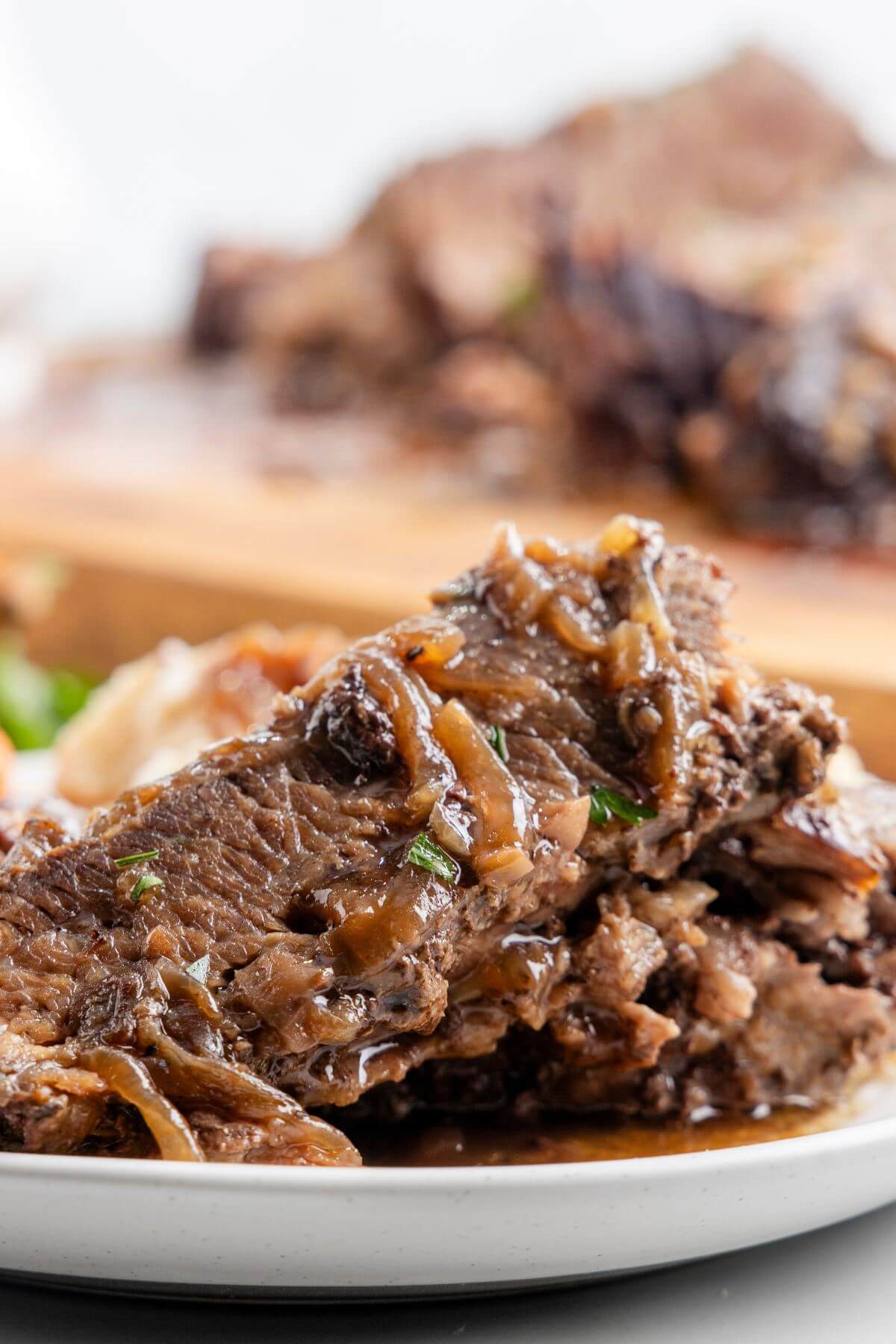 A close up of the brisket shows gravy and herbs on top.