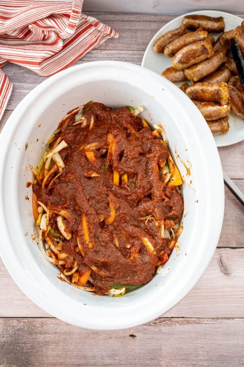 Marinara sauce covers vegetables in a white crock pot.