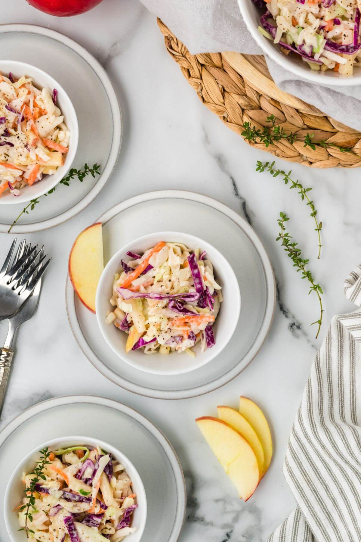 A wicker platter holds a bowl of coleslaw with other full bowls next to it.